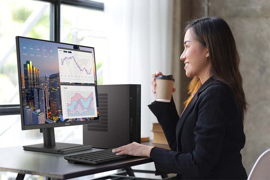 Veri analizi ve grafiklerle çalışan kadın ofis çalışanı, bilgisayar ve monitör kullanarak finans ve oyun verilerini inceliyor, profesyonel çalışma ortamında.