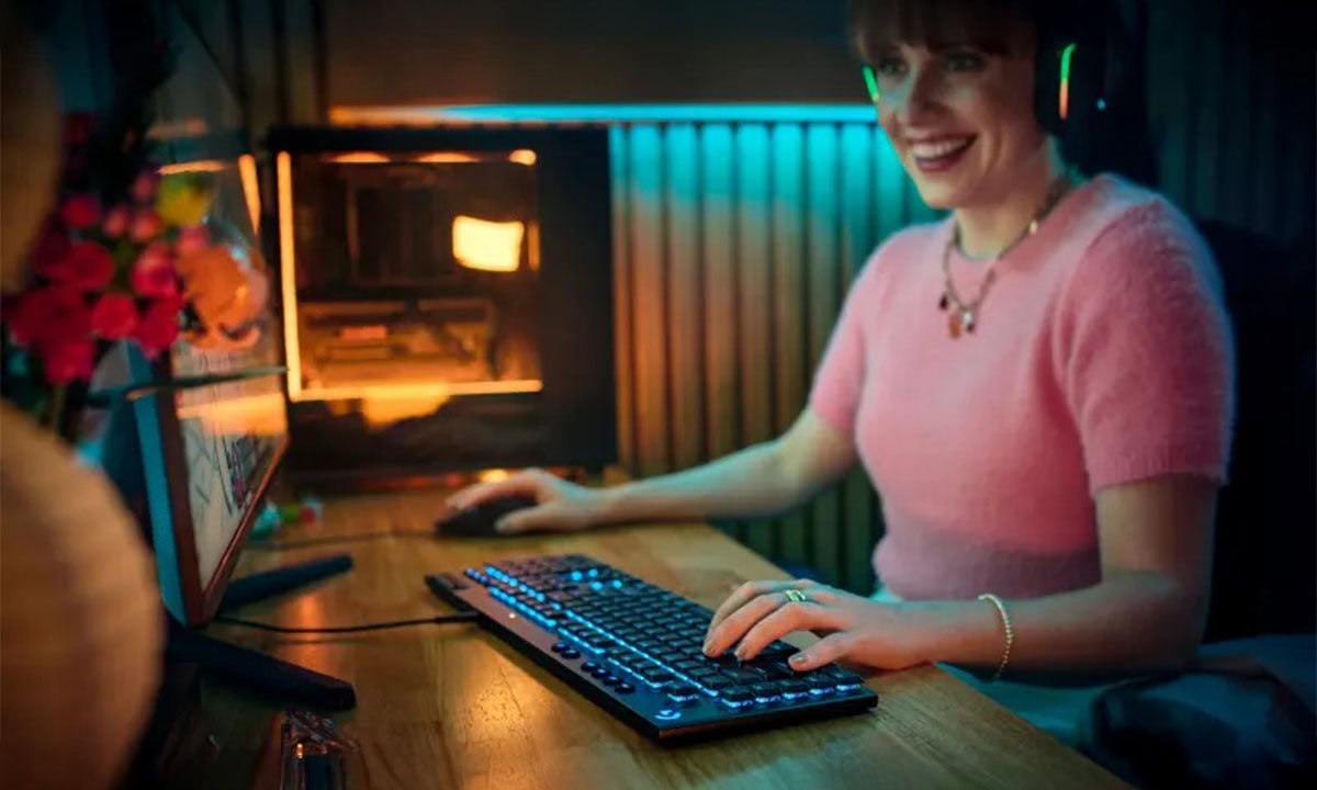 Sesli oyun ve e-spor meraklısı genç kadın, RGB aydınlatmalı klavye ve kulaklık kullanıyor, oyun bilgisayarında oynarken eğleniyor ve odasında modern gaming ortamında zaman geçiriyor.
