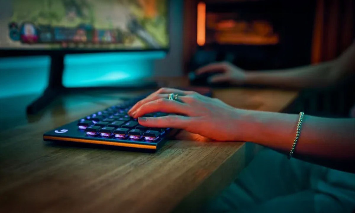 Yüksek performanslı gaming klavye ve monitörle bilgisayar oyunları oynayan kişinin el hareketleri, modern oyun deneyimini ve ışıklı klavye tasarımını gösteriyor.