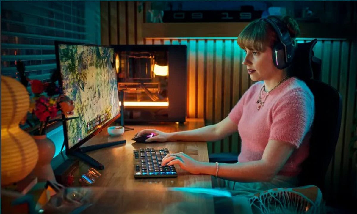 Oyun oynayan genç kadın, bilgisayar oyuncu seti ve yüksek çözünürlüklü ekran kullanıyor, oyun odasında renkli ışıklar ve ses ekipmanlarıyla gamer aktiviteye odaklanmış durumda.