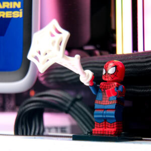 Kedi vakası Lego Spiderman figürü, renkli LED ışıklar ve bilgisayar donanımları arka planında, oyun ve teknolojiyi temsil eden eğlenceli görsel.