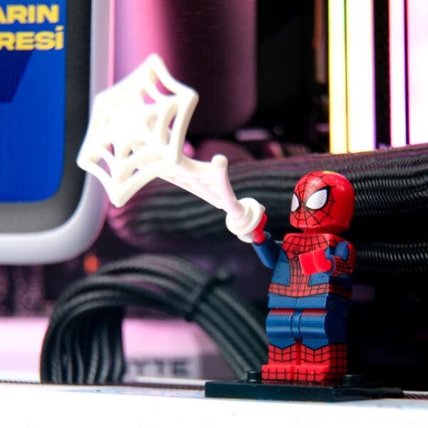 Kedi vakası Lego Spiderman figürü, renkli LED ışıklar ve bilgisayar donanımları arka planında, oyun ve teknolojiyi temsil eden eğlenceli görsel.