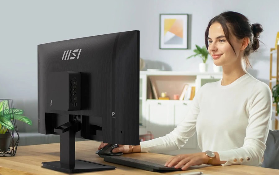 Kadın çalışan, masa başında bilgisayar kullanıyor, modern ofis ortamında, ergonomik çalışma alanı, teknolojik ekipmanlar ve doğal ışık ile aydınlatılmış.